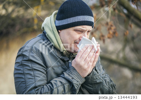 Man with napkin near nose at outdoors on the bench  13444193