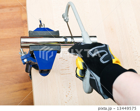 plumber saws metal trap pipe gripped in vice 13449575