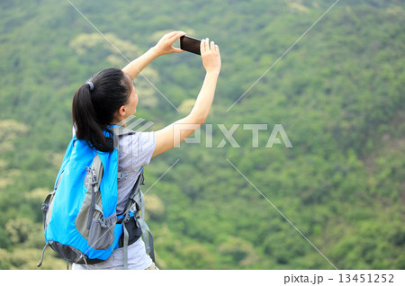 hiking woman taking photo with smart phone at mountain peak hiking woman taking photo with smart phone at mountain peak 13451252