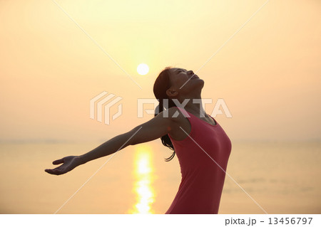 cheering woman open arms under the sunrise at sea  13456797