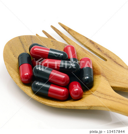 Oral medication red and black capsules in a table spoon on white background. Oral medication red and black capsules in a table spoon on white background. 13457844
