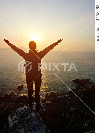 cheering hiking woman open arms to the sunrise stand at seaside mountain  13458392