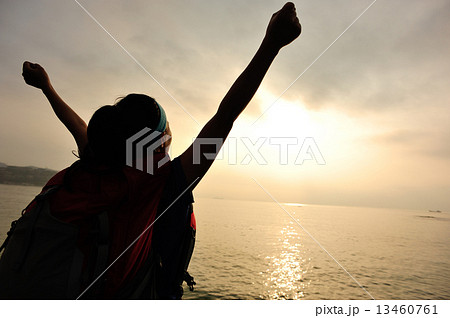 cheering hiking woman open arms to the sunrise stand at seaside mountain  13460761