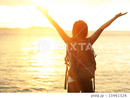 cheering woman hiker open arms to the sunrise stand at seaside  13461326
