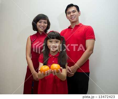 Portrait of a family of three Asian in red posing with mandarin oranges for Lunar / Chinese new year 13472423