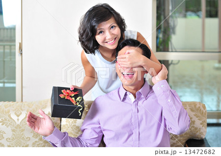 A beautiful Asian lady surprise her lover / boyfriend / husband from behind with her token of love  13472682