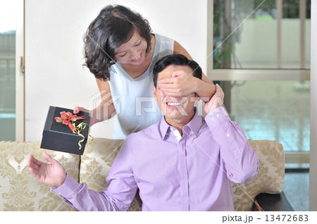 A beautiful Asian lady surprise her lover / boyfriend / husband from behind with her token of love  13472683