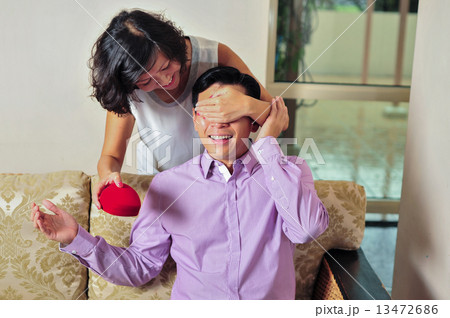 A beautiful Asian lady surprise her lover / boyfriend / husband from behind with her token of love  13472686