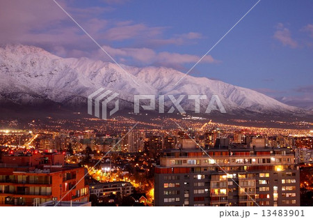 南米チリ共和国の首都サンチアゴ市の夕景、夕焼けに染まる山岳地帯を背景に街の灯りが美しく浮かび上がる。 13483901