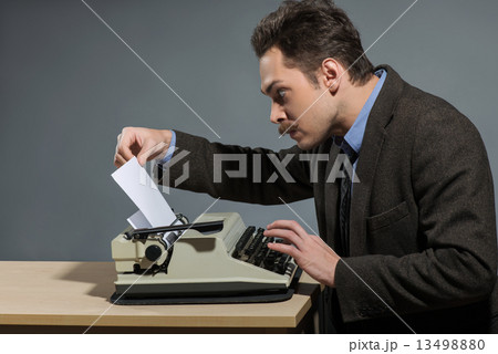 Happy young author typing at typewriter 13498880