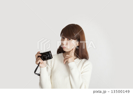 コンパクトデジカメの操作で疑問を持つ女性イメージ 13500149