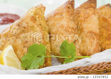 Samosas - Deep fried stuffed pasties with lemon wedges and dips  13507852