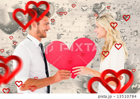 Composite image of attractive young couple holding red heart Composite image of attractive young couple holding red heart 13510784
