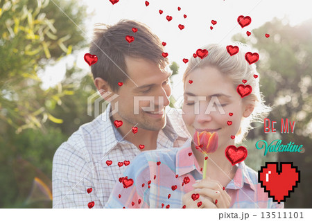 Composite image of young couple holding a flower in park Composite image of young couple holding a flower in park 13511101