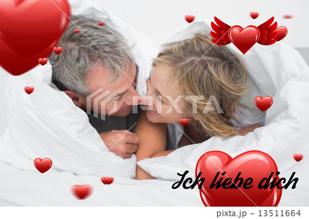 Composite image of loving middle aged couple under the duvet Composite image of loving middle aged couple under the duvet 13511664