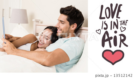 Composite image of attractive couple lying in bed with tablet pc Composite image of attractive couple lying in bed with tablet pc 13512142