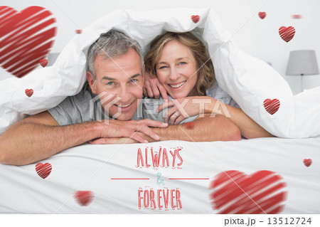 Composite image of cheerful couple under the duvet Composite image of cheerful couple under the duvet 13512724