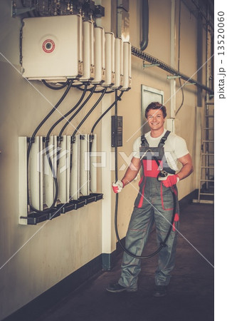 Cheerful serviceman holding hose with unbottled motor oil in a car workshop 13520060