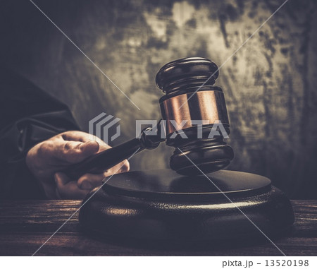 Judge's hand holding wooden hammer Judge's hand holding wooden hammer 13520198