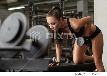 Exciting brunette exercising with dumbbells in gym 13528522
