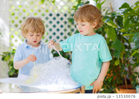 Two cute friend boys making experiment with colorful bubbles Two cute friend boys making experiment with colorful bubbles 13530076