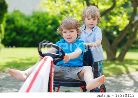 Two funny little boys having fun with race car outdoors Two funny little boys having fun with race car outdoors 13530115