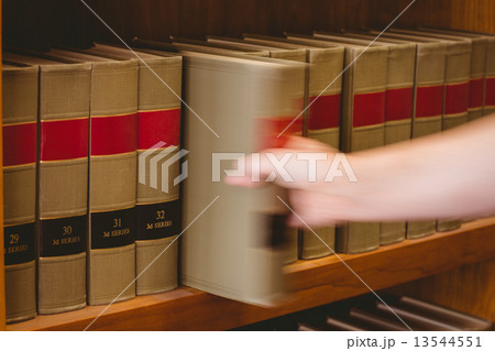 Hand taking a book from bookshelf 13544551