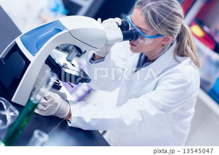 Science student looking through microscope in the lab 13545047