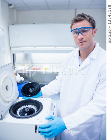 Chemist wearing safety glasses and using a centrifuge Chemist wearing safety glasses and using a centrifuge 13545138