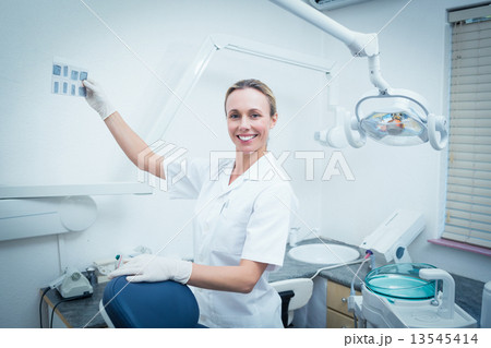 Smiling female dentist looking at x-ray Smiling female dentist looking at x-ray 13545414