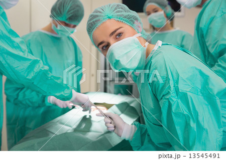 Medical student looking at camera during practice surgery 13545491