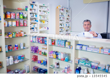 Pharmacist with grey hair holding a prescription 13545545