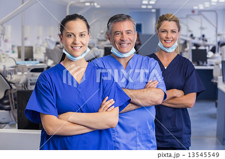 Portrait of smiling co-workers in a line with arms crossed 13545549