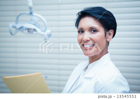 Smiling female dentist reading reports 13545551