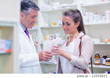 Pharmacist giving paper bag to his customer 13545621