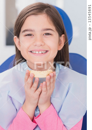 Smiling young patient holding teeth Smiling young patient holding teeth 13545691