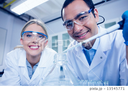 Science students using pipette to fill beaker 13545771