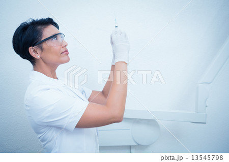 Female dentist in surgical mask holding injection 13545798