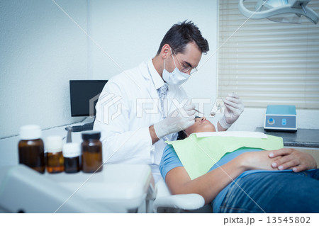 Male dentist examining womans teeth 13545802