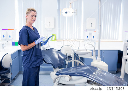 Smiling dentist working on tablet pc and looking at camera 13545803