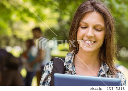 Smiling student with a shoulder bag and using tablet computer Smiling student with a shoulder bag and using tablet computer 13545818