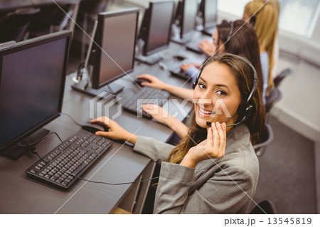 Smiling call centre agent talking on the headset 13545819