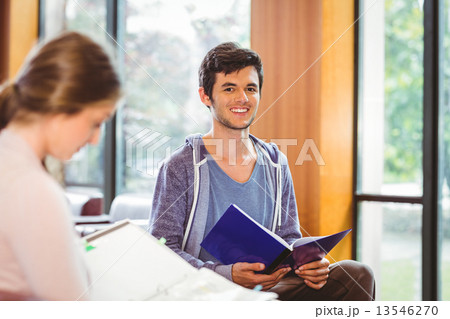 Students sitting on couch revising and smiling at camera 13546270