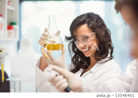 Pretty science student smiling and holding beaker Pretty science student smiling and holding beaker 13546401