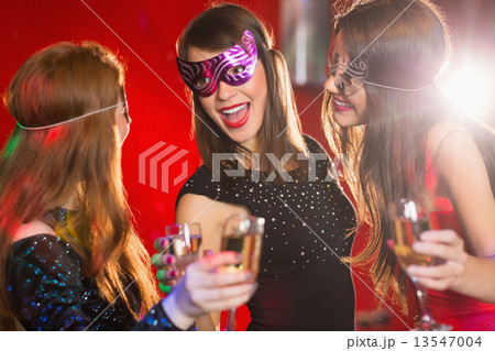 Friends in masquerade masks drinking champagne 13547004