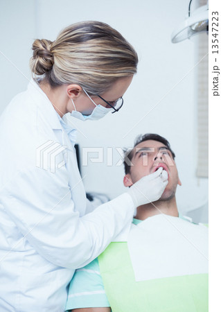 Female dentist examining mans teeth 13547223
