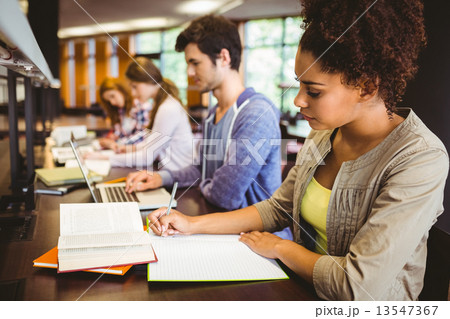 Focused students sitting in a line writing 13547367
