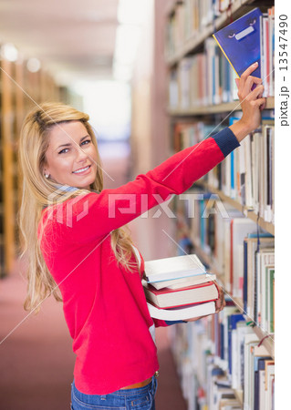 Mature student picking out book in library 13547490