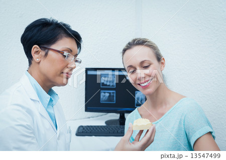 Dentist showing woman prosthesis teeth 13547499