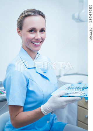 Female dentist in blue scrubs holding tray of tools Female dentist in blue scrubs holding tray of tools 13547509